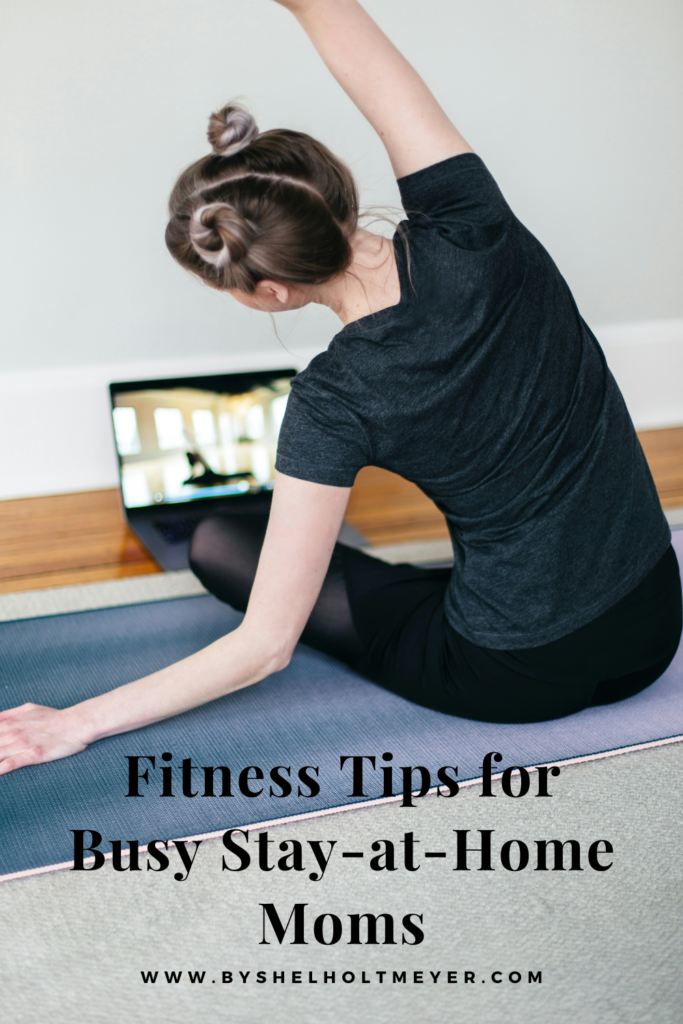 A mother doing yoga from the comfort of her living room with the blog post title overlayed stating "fitness tips for busy stay-at-home moms"